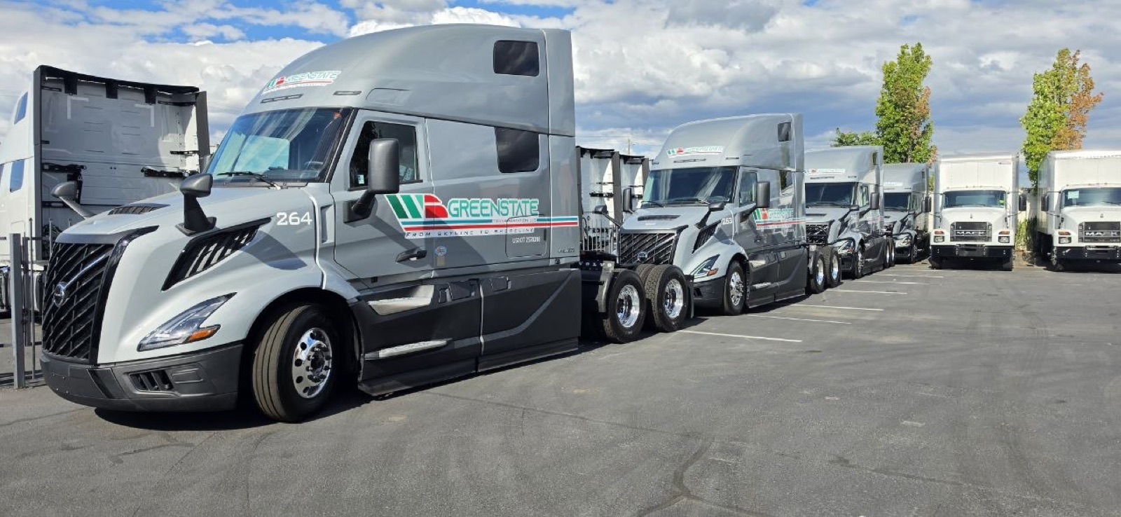 Row of grey Greenstate Volvo VNL trucks in the yard